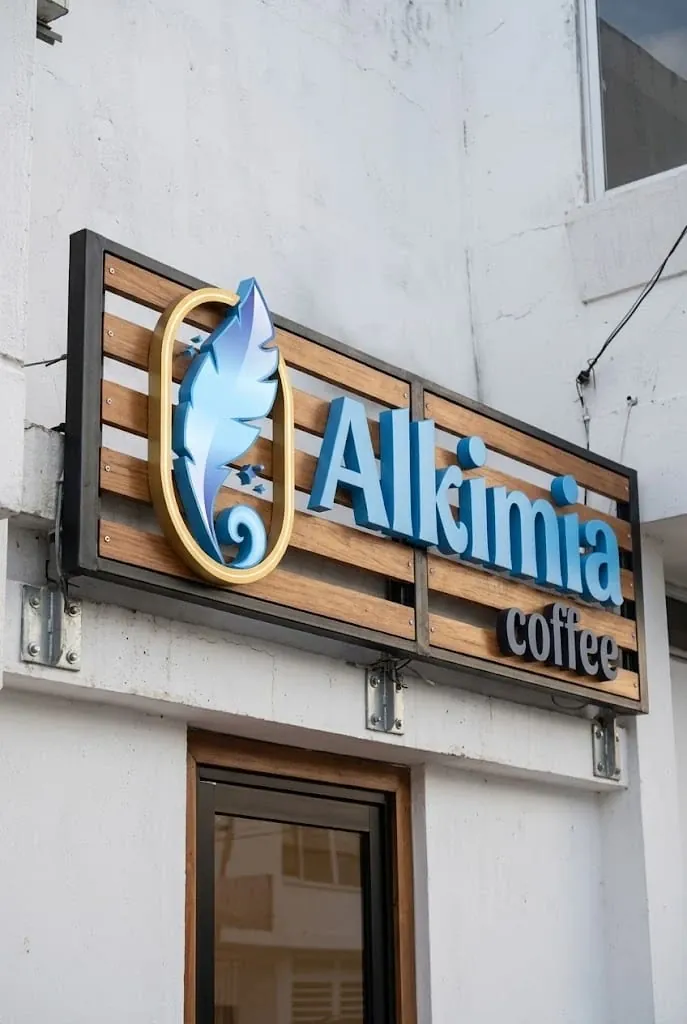 Letrero de Alkimia coffee sobre listones de madera, con la pluma azul dentro de un óvalo dorado